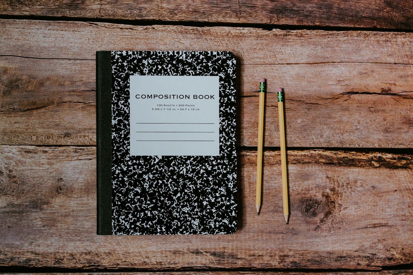 Comp book and #2 pencils laying on wood. Photo by Kelly Sikkema, Unsplash.