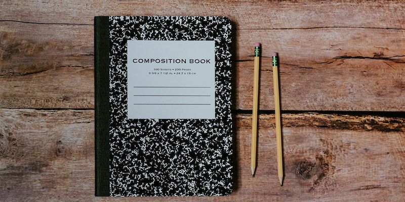 Comp book and #2 pencils laying on wood. Photo by Kelly Sikkema, Unsplash.